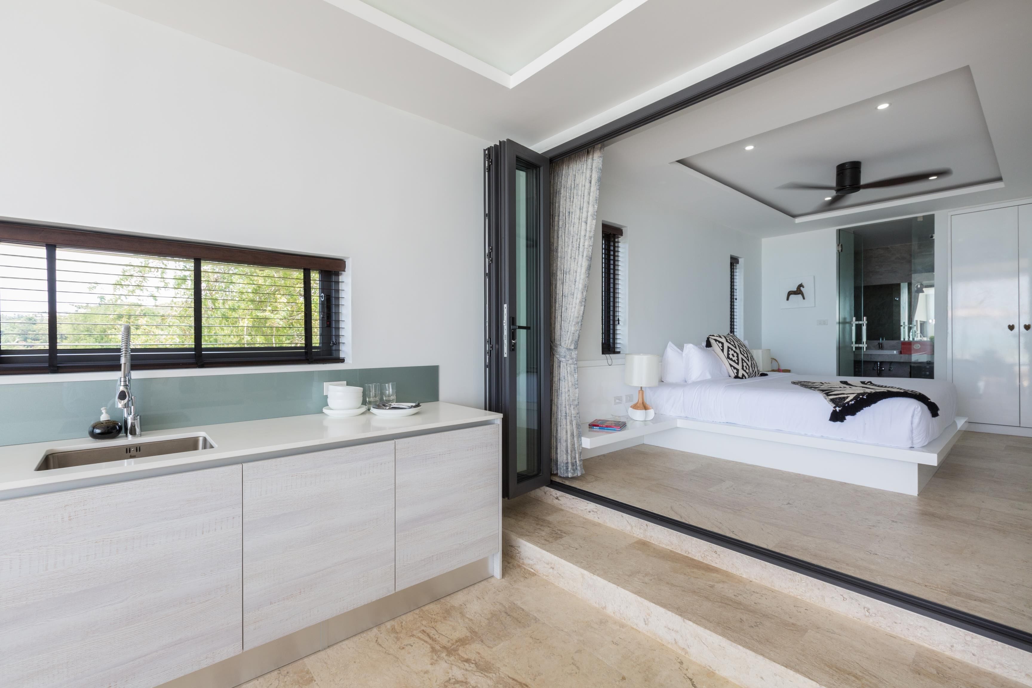 A modern bedroom with a large bed, a bedside table, and a view of the bathroom through a glass door.