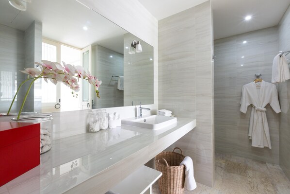 A modern bathroom with a large mirror, two sinks, a red cabinet, and a wicker basket. - Skye Beach Hotel (Koh Samui)