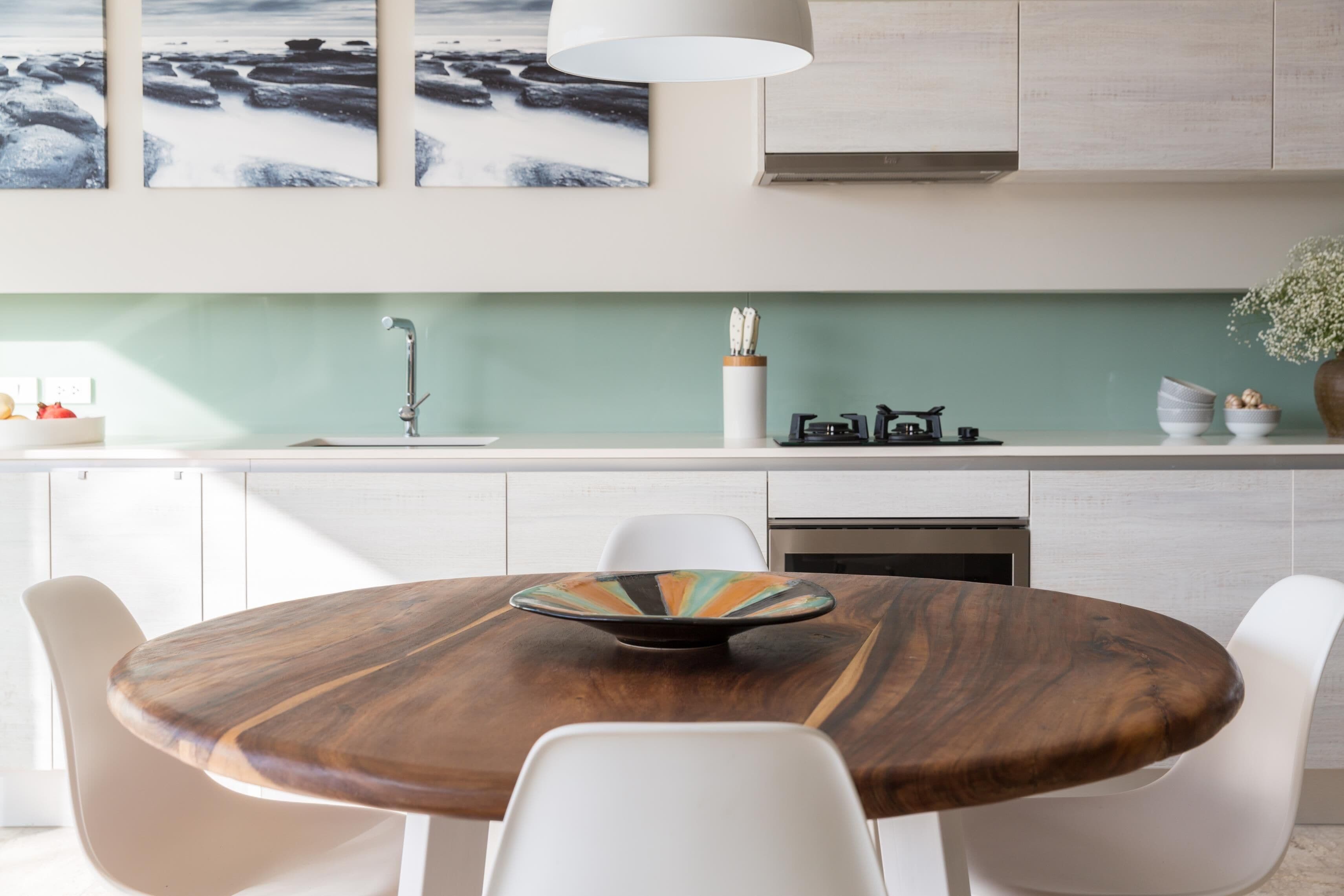 Une cuisine moderne avec une table ronde en bois, des chaises blanches et un pare-feu vert.