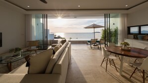 Una sala de estar moderna con un amplio ventanal que da a un balcón con vistas al mar.