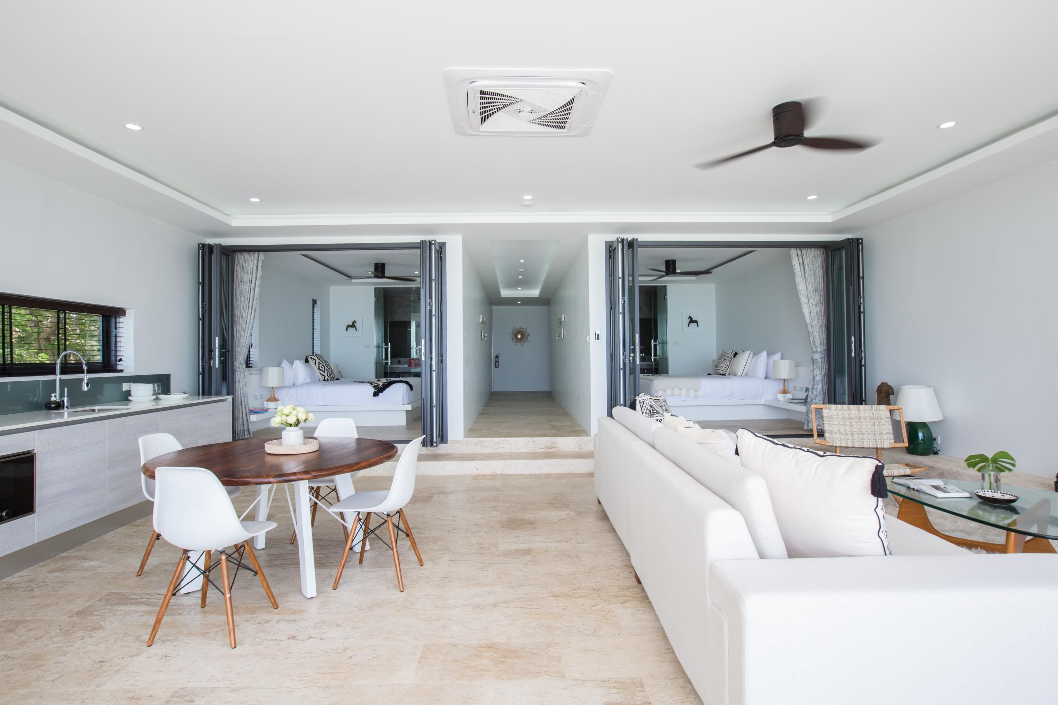 A modern hotel room with a dining area, a sofa, and a bed.