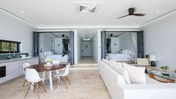 A modern hotel room with a dining area, a sofa, and a bed.