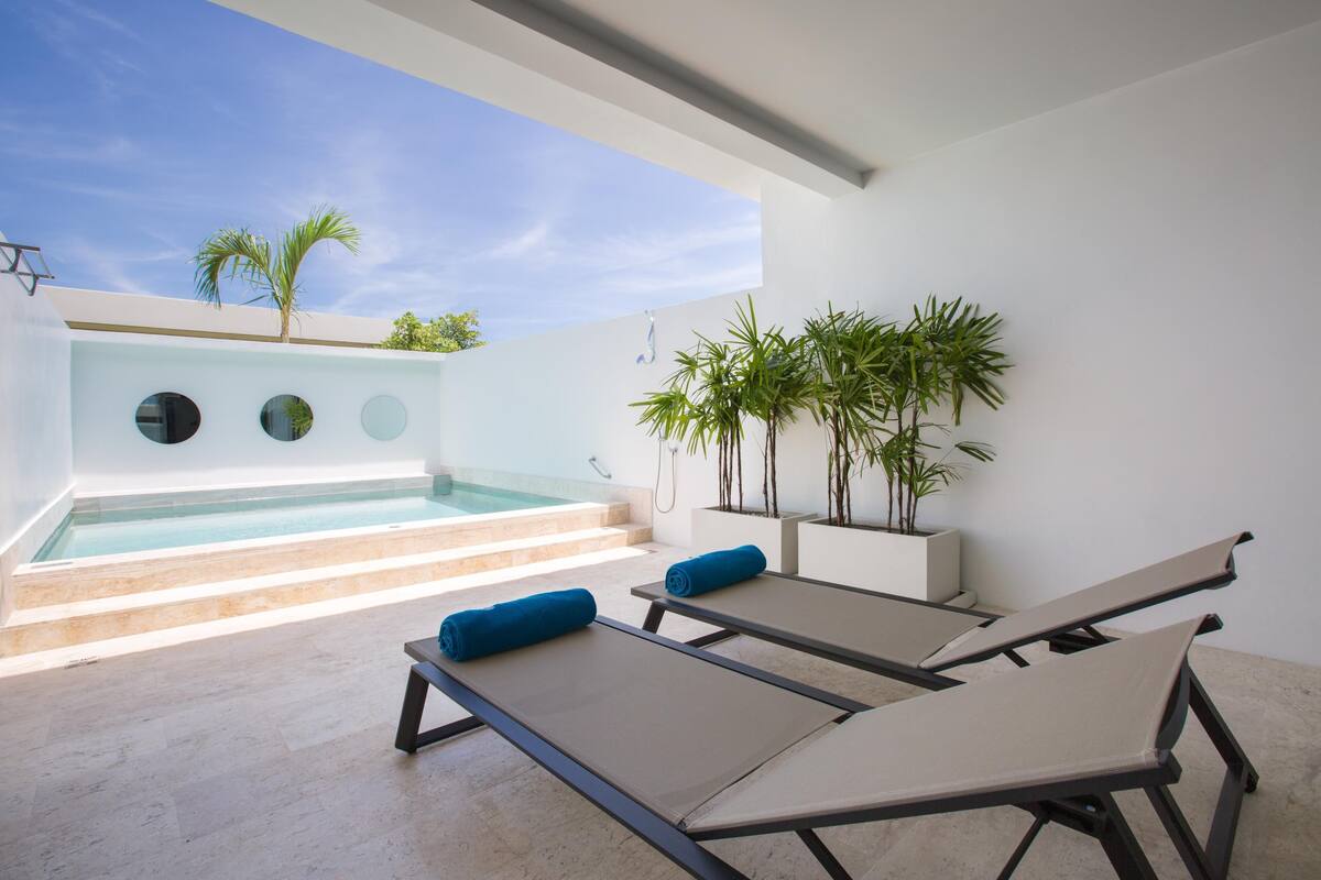 A modern outdoor pool area with two lounge chairs and a small pool.
