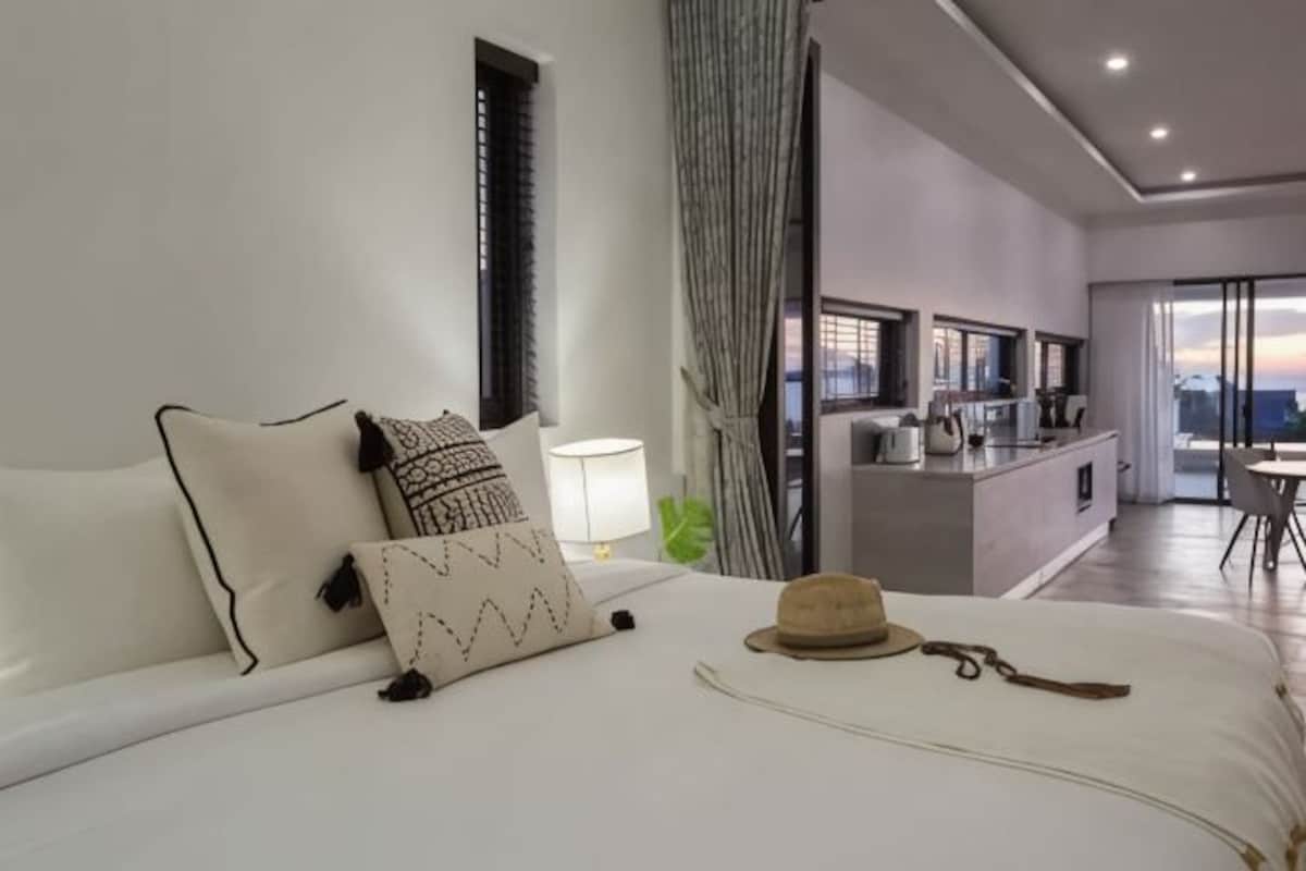 A modern hotel room with a bed, a desk, and a view of the city.