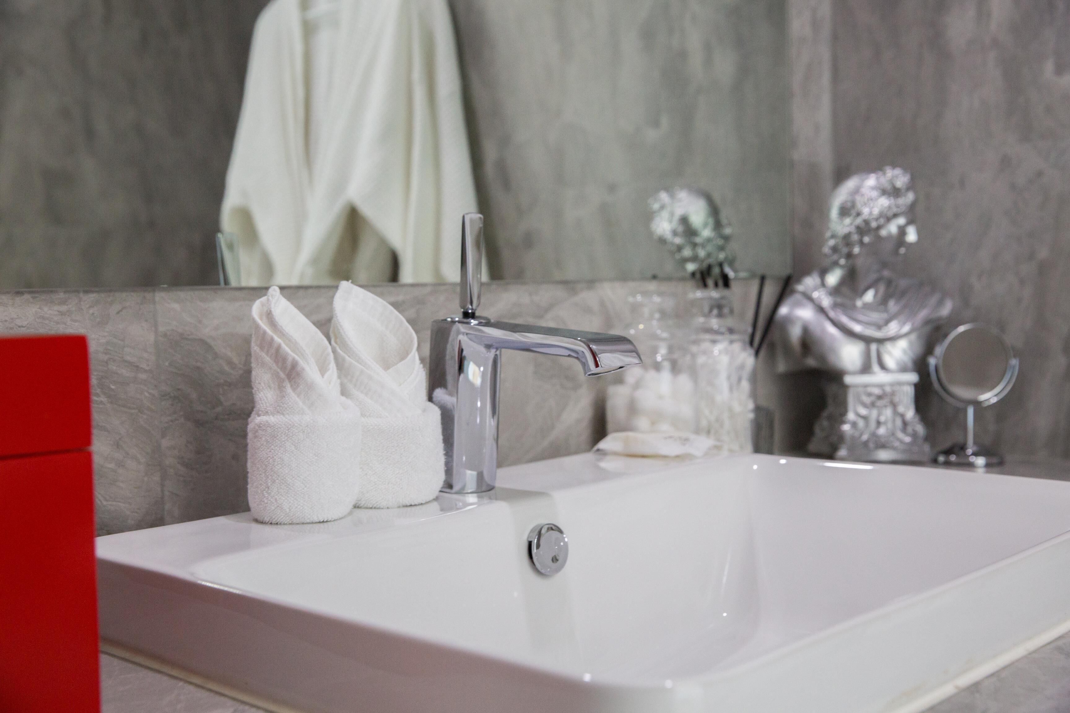 Un baño con un lavabo blanco, dispensador de toallas y un busto decorativo.