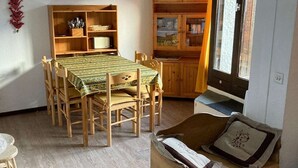 Un comedor con una mesa y sillas de madera, un armario de madera con estantes, y una ventana con cortinas.