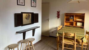 Un comedor con una mesa y sillas de madera, un banco y un estante en la pared con utensilios de cocina.