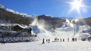 Une piste de ski enneigée, avec un chalet et un ciel bleu dégagé.