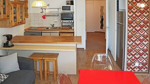 A compact kitchen with a wooden countertop, a built-in oven, a microwave, and a coffee maker. There is a small dining area with a red table and two stools. - 2-room apartment for 6 people above the mall, Les Orres (Les Orres)