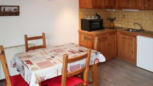 A kitchen with wooden cabinets, a microwave, a sink, and a table with a checkered tablecloth.