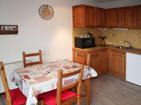 Una cocina con armarios de madera, un microondas, un lavamanos y una mesa con mantel a cuadros.