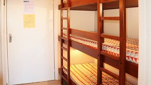 A bunk bed room with a white door, a wooden ladder, and a patterned bedspread.