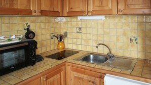 A kitchen with wooden cabinets, a microwave, a sink, and a tiled backsplash.