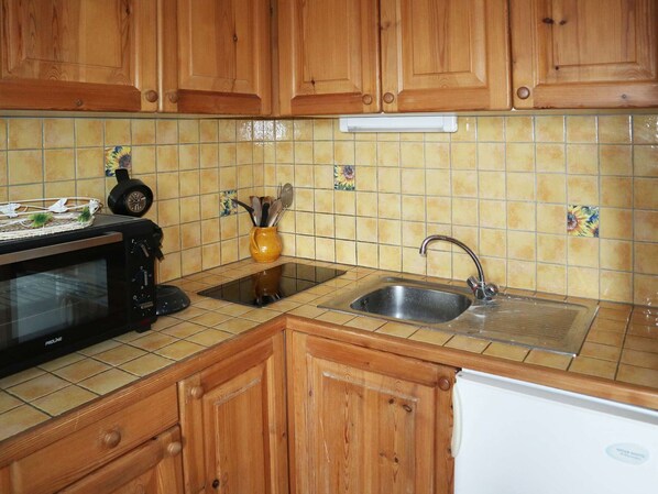 Una cocina con armarios de madera, microondas, fregadero y salpicadero de azulejos.