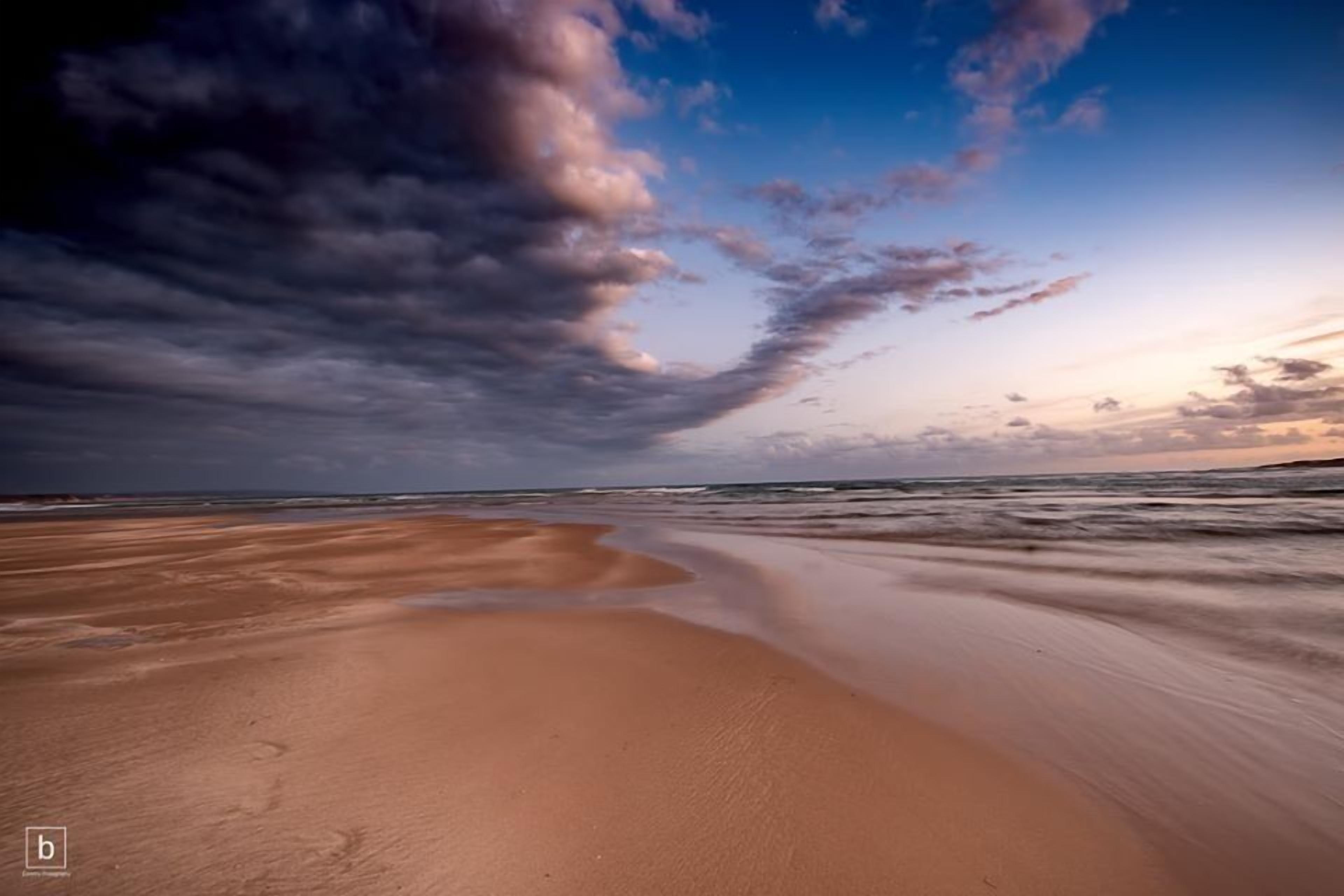 Una playa con una amplia extensión de arena y olas suaves.