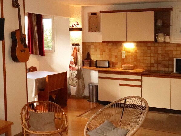 Una cocina acogedora con comedor, que incluye una guitarra, sillas de mimbre y un salpicadero de azulejos.