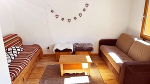 A cozy living room with a striped sofa, a brown sofa, a wooden coffee table, and a small bench. - Superb 10 pax duplex with pool and jacuzzi in Les Orres 1800 (Les Orres)