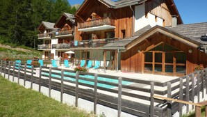 A wooden chalet with a pool, multiple balconies, and outdoor seating. - Renovated apt with pool, sauna, hammam and wifi at Les Orres 1800 (Les Orres)