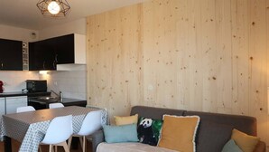 A compact living space with a kitchenette, a dining area, and a sofa with decorative pillows. - Renovated apt with pool, sauna, hammam and wifi at Les Orres 1800 (Les Orres)