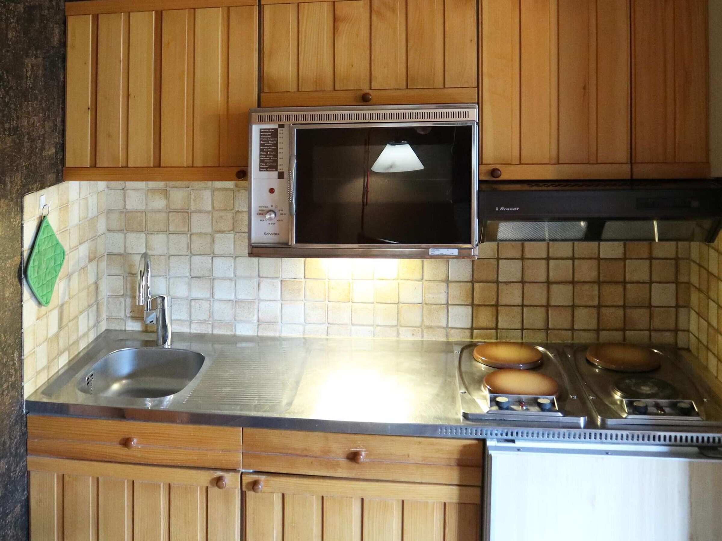 A kitchen with wooden cabinets, a microwave, a sink, and a stove.
