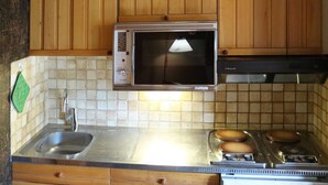 A kitchen with wooden cabinets, a microwave, a sink, and a stove. - Ski-in/ski-out studio for 4, Place Emile Hodoul (Les Orres)