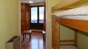 A room with a bunk bed, a small table, and a bench. There is a door leading to a balcony with a view of the outside. - Studio for 4 in central Les Orres, near slopes (Les Orres)