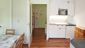 A compact room with a bed, a small kitchenette, a dining area, and a door leading to another room. - Studio for 4 in central Les Orres, near slopes (Les Orres)