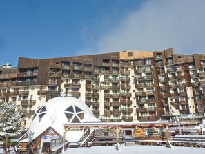 Un immeuble à plusieurs étages, doté de balcons et surmonté d’une grande structure en forme de dôme, qui se trouve au premier plan.