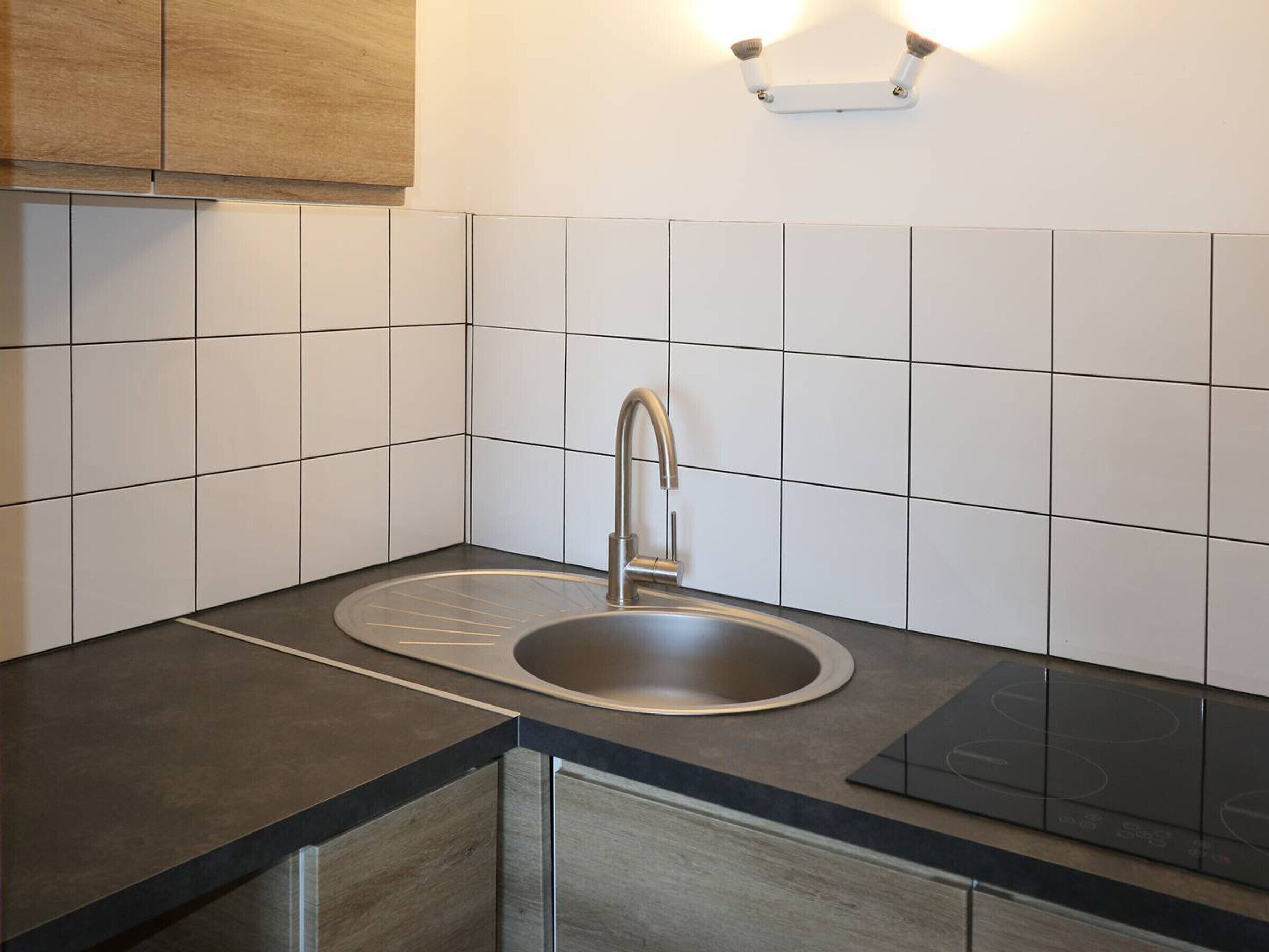 A modern kitchen with a double sink, a built-in stovetop, and wooden cabinets.