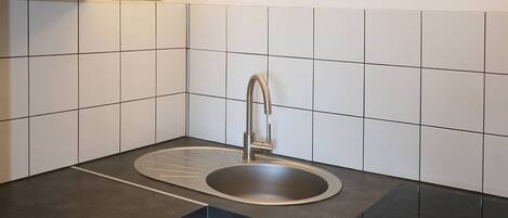 A modern kitchen with a double sink, a built-in stovetop, and wooden cabinets.