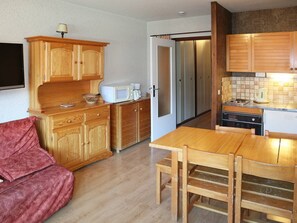A compact kitchen with wooden cabinets, a microwave, and a refrigerator.