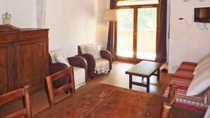 A wooden-floored living room with a sofa, chairs, a table, and a television. - Spacious 2-room apartment for 6 in the center with balcony, washer (Les Orres)