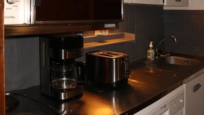 Ett modernt kök med en inbyggd kaffebryggare, brödrost och en diskho i rostfritt stål.