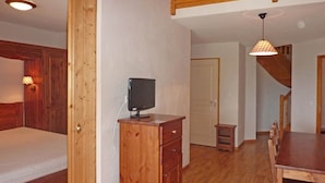 A room with a bed, a wooden desk with a computer, a dining table, and a staircase. - Cozy Apartment for 8 with Pool, Sauna, and Ski-In/Ski-Out Access in Les Orres 1800 (Les Orres)