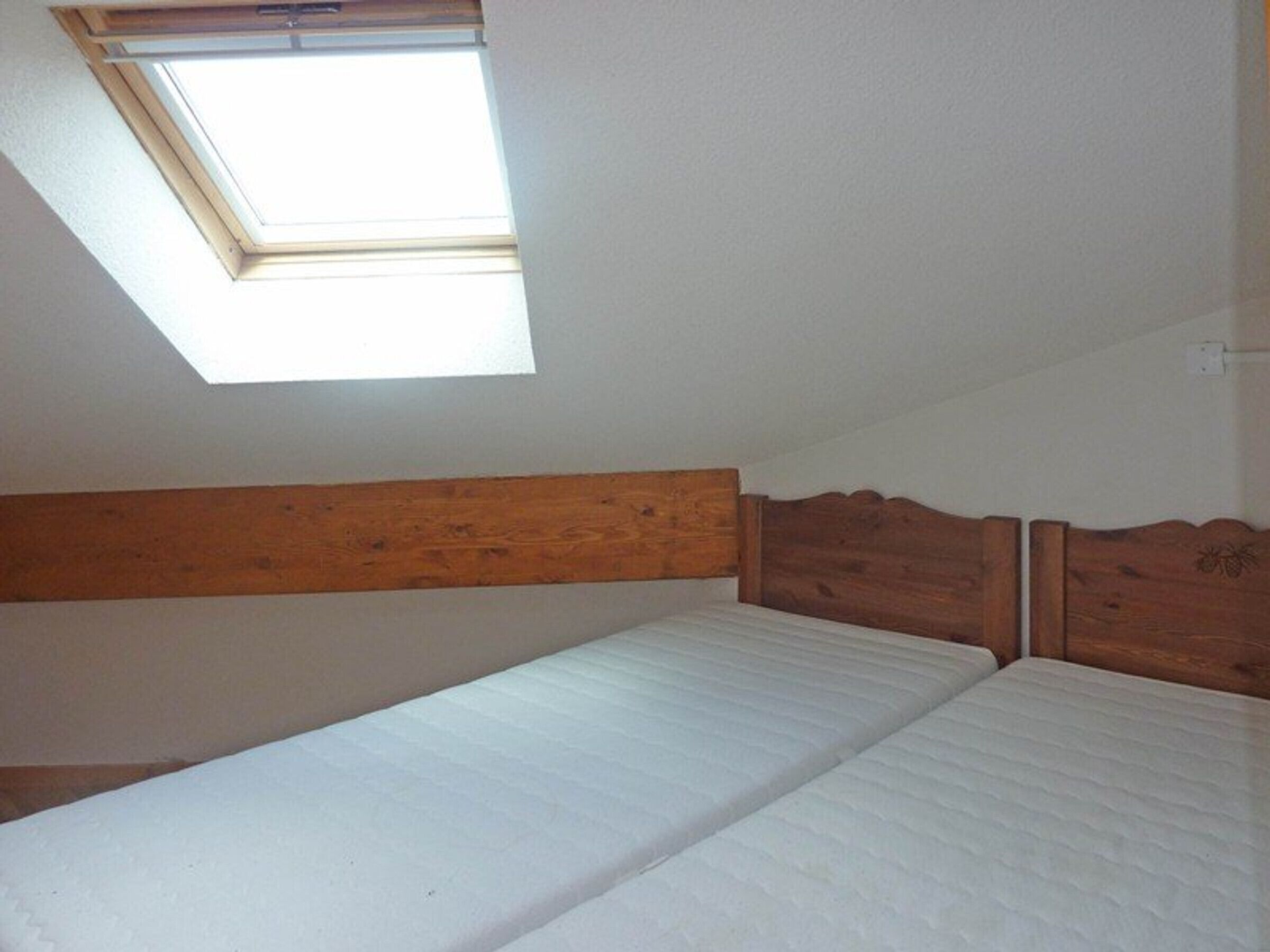 A small, single-bed room with a sloped ceiling and a skylight.
