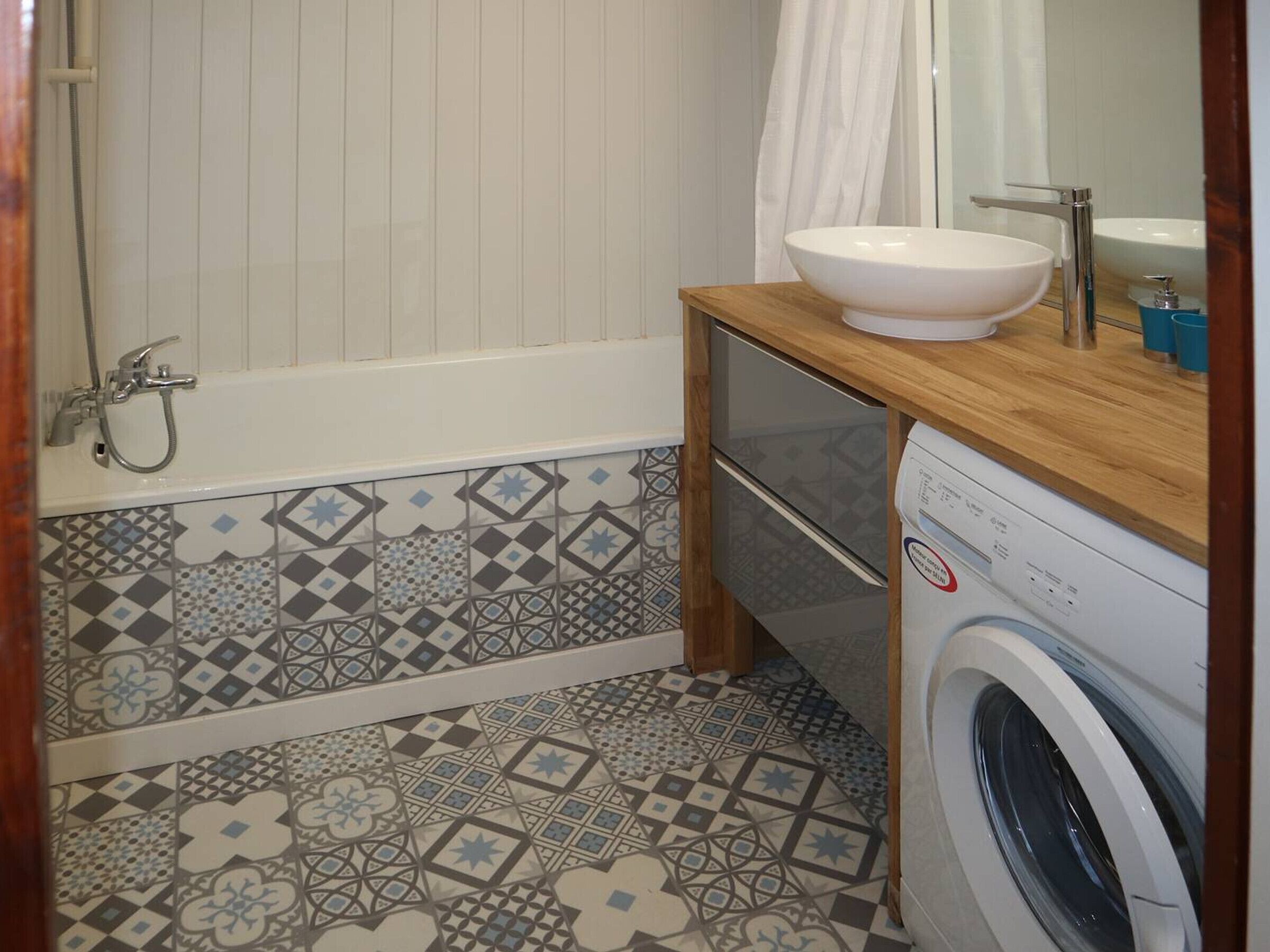 A small bathroom with a bathtub, a sink, and a washing machine.