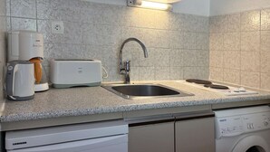 Una cocina con lavavajillas integrado, cafetera, tostadora y pileta.