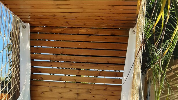 A wooden deck with a hot tub, a bottle of Shiraz wine, and a glass on a towel.