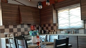 A modern kitchen with a dining area, featuring a checkered backsplash, wooden cabinets, and a central island with a sink.