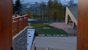 Vista de un paisaje montañoso con picos nevados y un edificio moderno con techo inclinado.