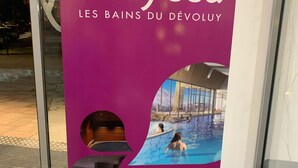 Exhibición promocional de O'dycéa Les Bains du Dévoluy que muestra una piscina, zona de spa y una URL de sitio web.