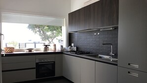 Una cucina moderna con mobili scuri, un'ampia finestra e un forno a incasso.