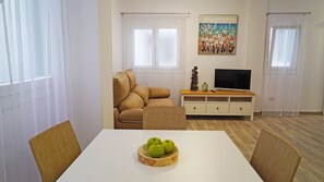 A living room with a beige sofa, a white TV stand, and a painting on the wall.