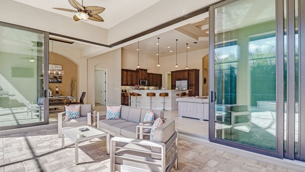 A spacious living area with a large glass sliding door, a modern kitchen with dark wooden cabinets, and a ceiling fan.
