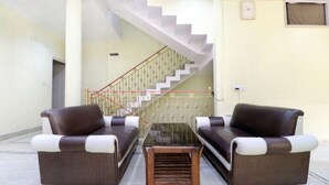 A living room with two brown sofas, a glass coffee table, and a staircase with a white railing.