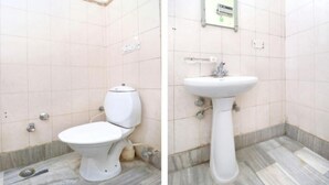 A bathroom with a toilet and a sink, tiled walls, and a marble floor.