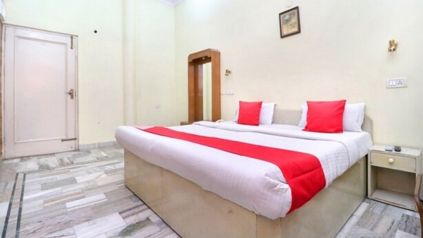 A bedroom with a large bed, a nightstand, a door, and a mirror on the wall.