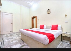 Un dormitorio con una cama grande, una mesita de noche, una puerta y un espejo en la pared.