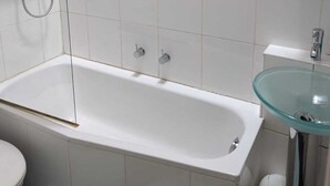 Un baño con bañera, lavabo de vidrio y retrete.