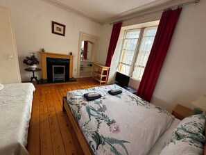 A bedroom with a bed, a fireplace, a desk, and a window with curtains. - Edinburgh Marchmont Meadows Flat. (Edinburgh)